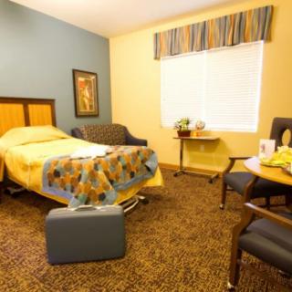 A neatly organized bedroom with a bed, chairs, and a window.
