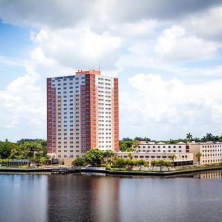A high-rise building overlooking a river on a cloudy day.