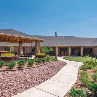 A beautifully landscaped outdoor area with a walkway leading to a pavilion and building.
