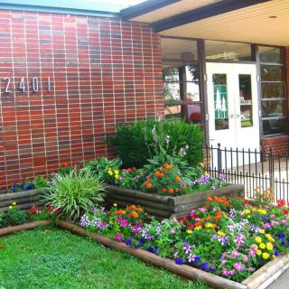 A well-maintained garden with colorful flowers in front of a brick building entrance.