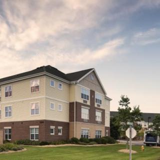 A suburban apartment complex with well-maintained landscaping under a cloudy sky.