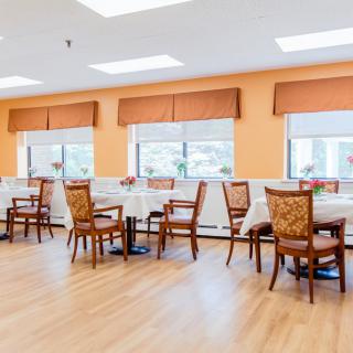 A bright and spacious dining room with neatly arranged tables and chairs.