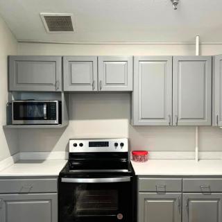 A modern kitchen featuring gray cabinets, a microwave, and an electric stove.