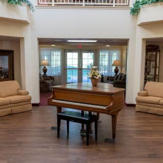 A spacious living room featuring a grand piano and comfortable seating.