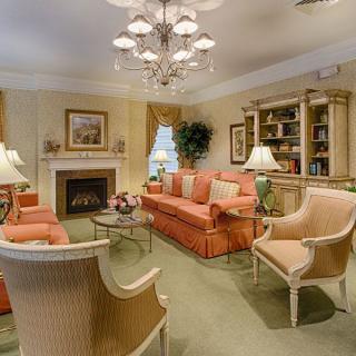 A cozy living room with elegant furniture, including a sofa and armchairs, centered around a fireplace and adorned with tasteful decor.