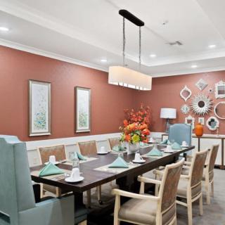 A modern dining room with elegant decor and a set table, featuring framed art and unique wall-mounted mirrors.