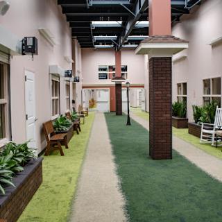 A serene indoor courtyard featuring a pathway lined with benches and greenery.