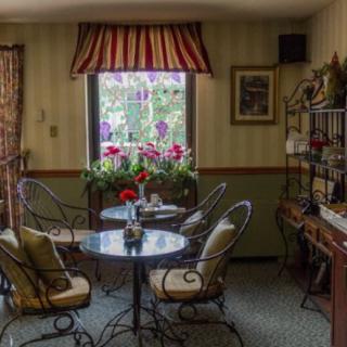 A cozy indoor caf setting with round tables and chairs, adorned with flowers by the window.