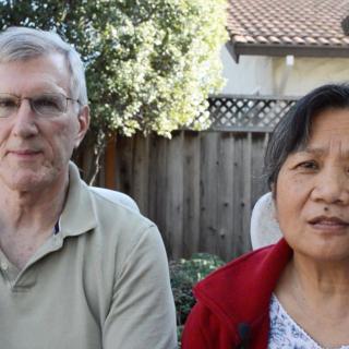 A couple sitting together in a garden on a sunny day.