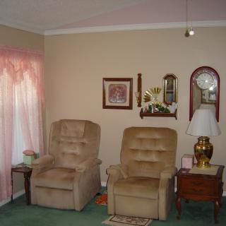 A cozy living room with two recliners, a floor lamp, and decorative wall items.