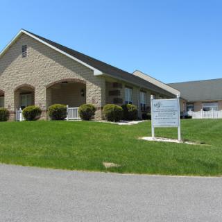 A well-maintained building with a welcoming facade surrounded by green grass under a clear blue sky.