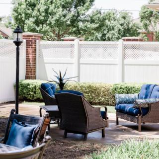 A cozy outdoor patio setup with chairs and a table, surrounded by greenery.