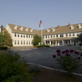 A large building with a U.S. flag in front, surrounded by landscaped greenery.