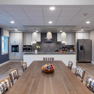 A modern kitchen and dining area featuring sleek cabinetry, a large wooden dining table, and stylish pendant lighting.