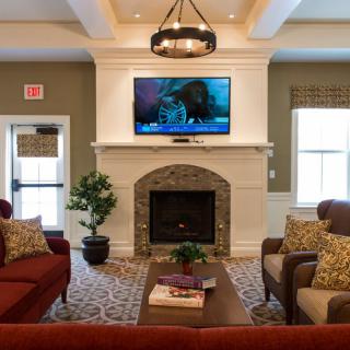 A cozy living room with a fireplace, television, and comfortable seating surrounded by elegant decor.