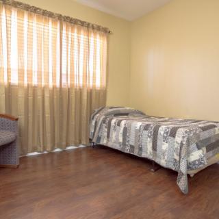 A minimalist bedroom with a single bed and wooden flooring.