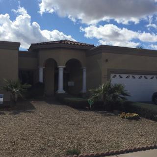 A suburban house with a garage and landscaped front yard under a cloudy sky.