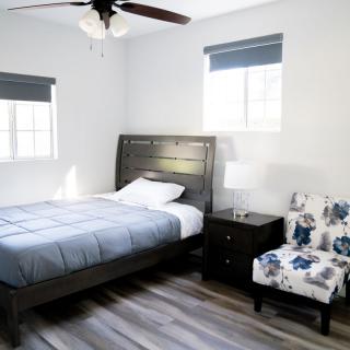 A modern bedroom with a bed, nightstand, and floral chair.