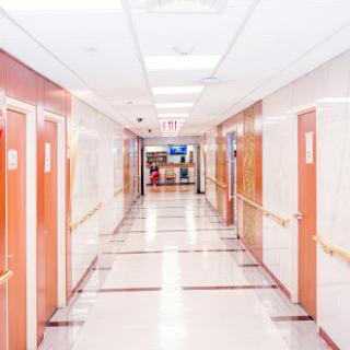 A bright and spacious hallway in a hospital, featuring multiple doors and soft lighting.