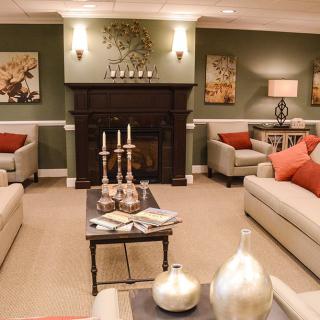 A cozy living room with neutral-toned sofas, a dark wooden fireplace, and decorative accents.