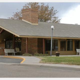 A single-story brick building with a sloped roof and an entrance path.