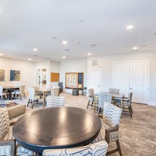 A spacious and modern community room with multiple seating arrangements and tables.