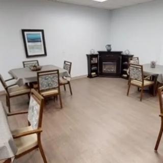A cozy dining room setup with several tables and chairs, featuring a fireplace along the wall.