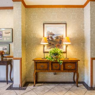 A warmly decorated hallway featuring a wooden table with lamps, artwork, and a plant.
