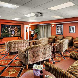 A modern lounge area with patterned sofas, a large TV screen, and artwork adorning the walls.