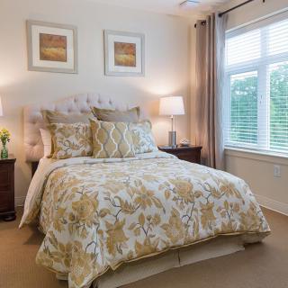 A cozy and well-decorated bedroom with a neatly made bed, soft lighting, and large window.