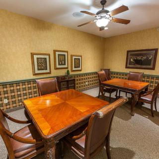 A cozy room with wooden tables and chairs, decorated with framed art and a ceiling fan.