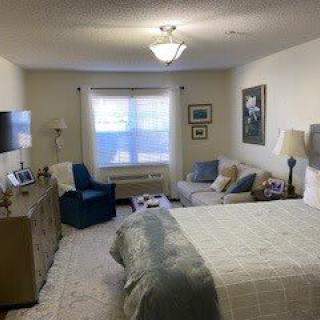 A cozy bedroom with a comfortable bed, seating area, and soft lighting.
