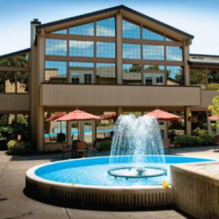 A hotel exterior with a central fountain and outdoor patio seating.