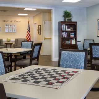 A community room with a chess board on the table, bookshelves, and an American flag in the background.