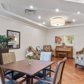 A cozy living room with comfortable seating, a piano, and decorative artwork.