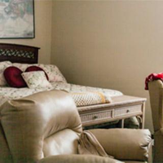 A cozy bedroom with a bed, armchair, and decorative pillows.