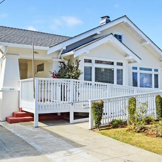 A charming white bungalow with a spacious porch and well-maintained landscaping.