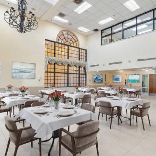 An elegant dining room with neatly arranged tables, adorned with chandeliers and decorative artwork on the walls.