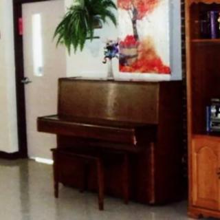 A cozy living space featuring an upright piano and colorful artwork.