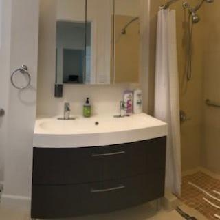 Modern bathroom with a curved vanity and a glass shower enclosure.