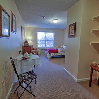 A cozy bedroom interior with a small table and chair, and neatly arranged decor.