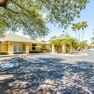 A sunny day view of a motel with a parking lot and surrounding trees.