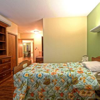 A cozy bedroom with colorful bedspread and wooden furniture.