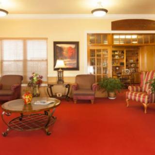 A cozy living room with red carpeting, comfortable armchairs, and elegant decor.