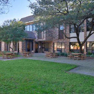 A serene courtyard view of a modern brick building surrounded by greenery.