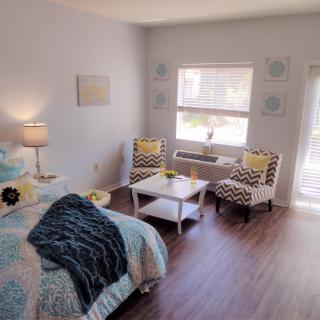 A cozy and modern bedroom interior with a bed, lamp, and seating area.