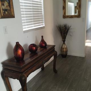 A well-decorated hallway with a wooden table adorned with vases, a mirror, and wall art.