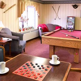 A cozy game room featuring a pool table and a checkers board with coffee cups on the side.