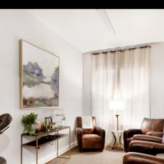 A cozy living room with leather chairs and a large painting on the wall.