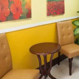 A cozy waiting area with two chairs and a small table, adorned with colorful paintings on the wall.